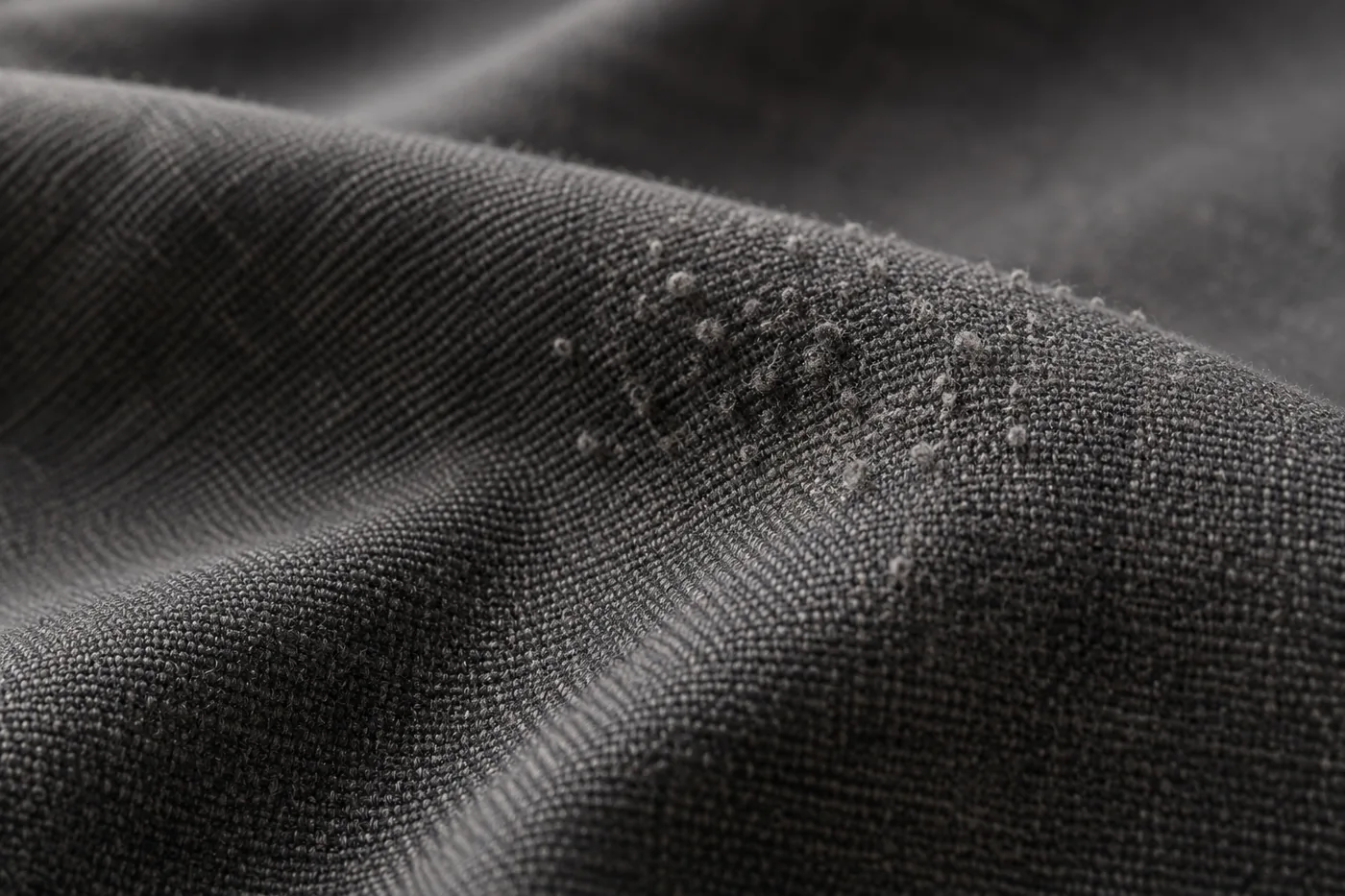 Close view of small surface pills on dark woven fabric.